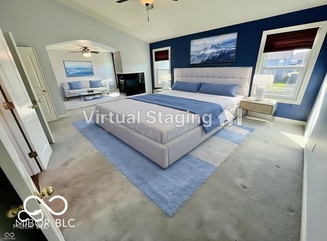 carpeted bedroom featuring multiple windows, vaulted ceiling, and ceiling fan