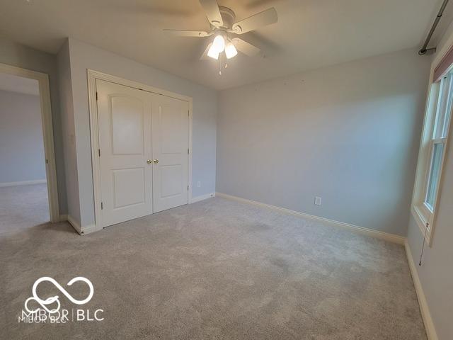 unfurnished bedroom with light carpet, ceiling fan, and a closet