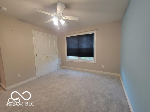 unfurnished bedroom with ceiling fan, light colored carpet, and a closet