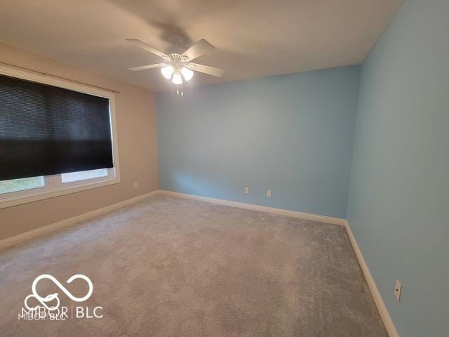 carpeted spare room featuring ceiling fan