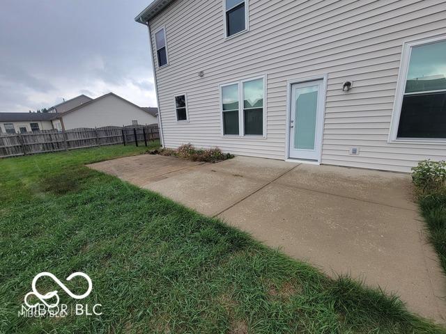 back of property with a lawn and a patio