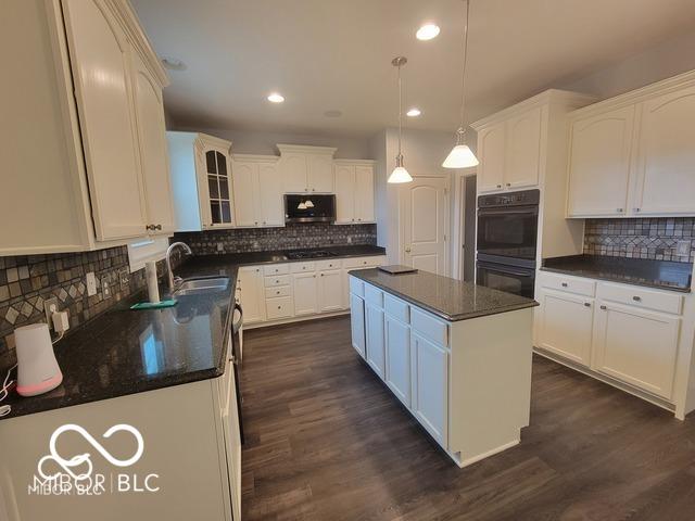 kitchen featuring sink, white cabinets, hanging light fixtures, a center island, and stainless steel appliances