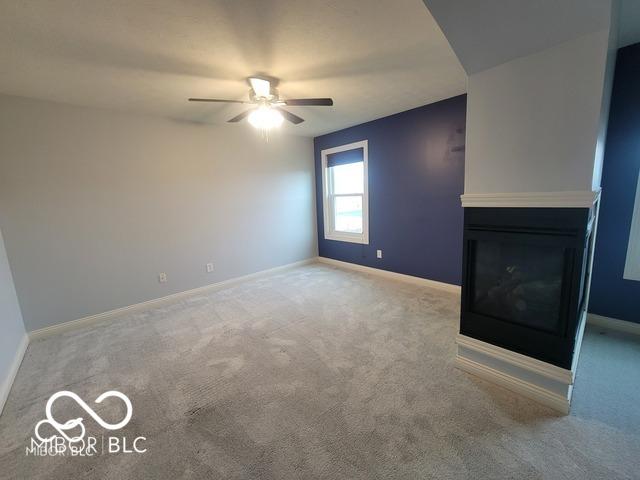 unfurnished living room featuring light carpet and ceiling fan