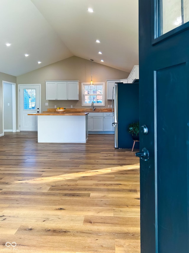 kitchen featuring stainless steel refrigerator, butcher block countertops, and white cabinets