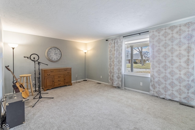 interior space featuring visible vents, light colored carpet, baseboards, and a textured ceiling