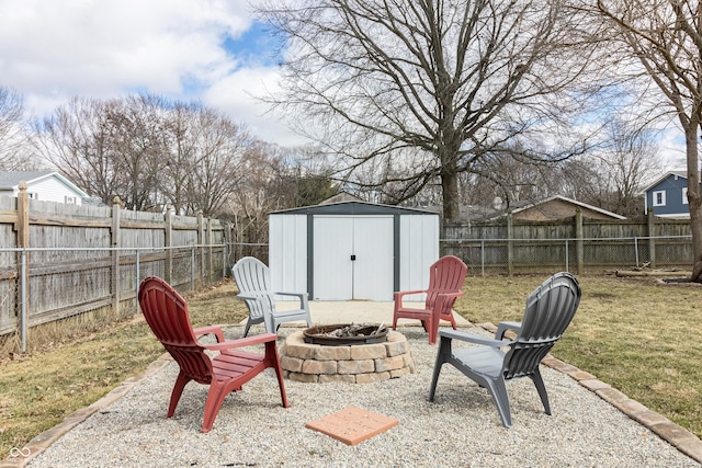 view of patio / terrace with an outbuilding, a fenced backyard, a shed, and an outdoor fire pit