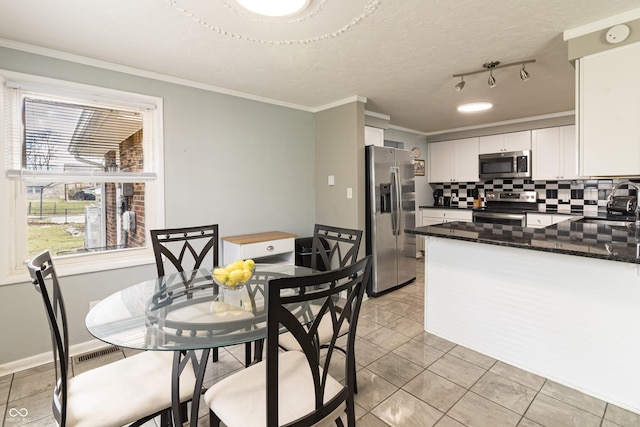 kitchen featuring ornamental molding, backsplash, white cabinetry, appliances with stainless steel finishes, and light tile patterned floors