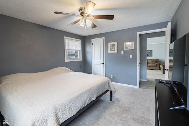 bedroom with light colored carpet, a textured ceiling, a ceiling fan, and baseboards