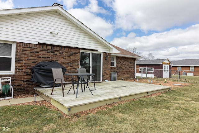 back of house featuring brick siding, fence, cooling unit, a deck, and a yard