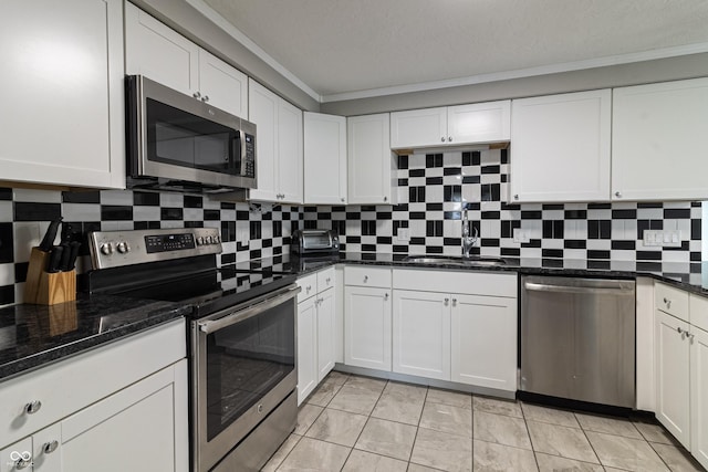 kitchen featuring backsplash, appliances with stainless steel finishes, white cabinetry, and a sink