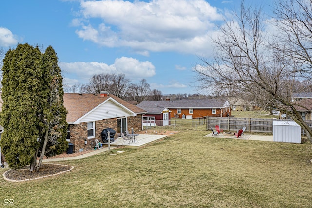 view of yard with a patio, an outbuilding, a shed, a fenced backyard, and a fire pit