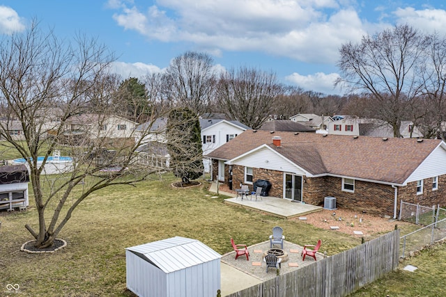 rear view of property featuring a fire pit, central air condition unit, a lawn, a fenced backyard, and a patio area