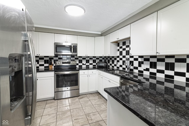 kitchen with white cabinetry, dark stone countertops, tasteful backsplash, and appliances with stainless steel finishes