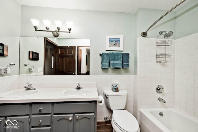 full bathroom featuring tile walls, tiled shower / bath combo, vanity, a textured ceiling, and toilet