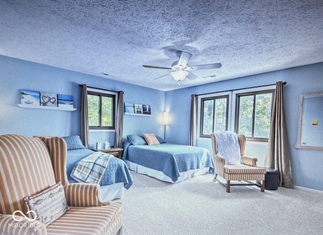 carpeted bedroom featuring ceiling fan and a textured ceiling