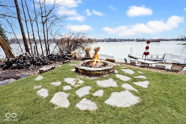 view of yard with a water view, a dock, and an outdoor fire pit