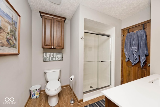 bathroom with toilet, an enclosed shower, a textured ceiling, vanity, and hardwood / wood-style floors