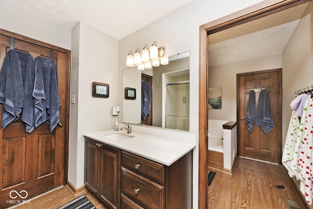 bathroom featuring vanity, hardwood / wood-style floors, a textured ceiling, and a shower with shower door