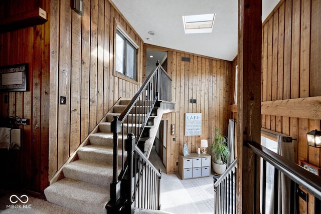 stairway with a skylight and wood walls