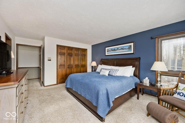 bedroom with light colored carpet, a closet, and a textured ceiling