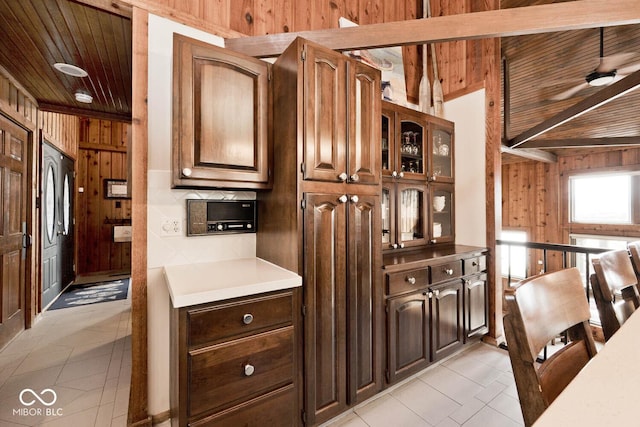 kitchen with light tile patterned flooring, refrigerator, wood ceiling, and wooden walls