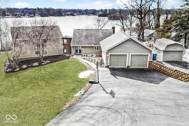 view of front of property with a shed, a garage, a front yard, and a water view