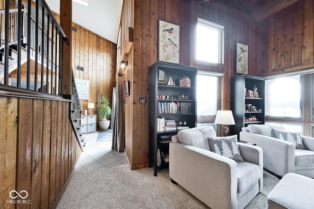 living room featuring high vaulted ceiling, light colored carpet, and wooden walls