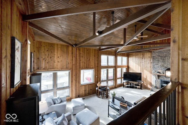 carpeted living room featuring beamed ceiling, high vaulted ceiling, a brick fireplace, and wood walls