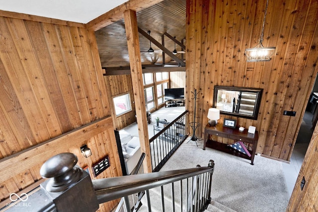 stairway featuring ceiling fan, carpet flooring, beam ceiling, and wood walls