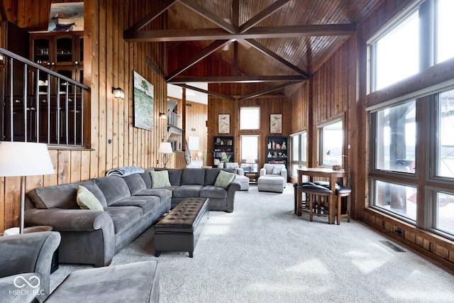 living room with high vaulted ceiling, wood walls, beamed ceiling, carpet, and wood ceiling