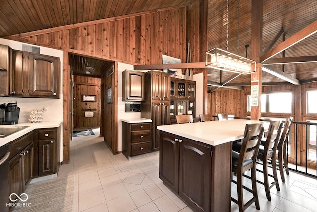 kitchen with dark brown cabinetry, a kitchen island, a breakfast bar, and wood walls