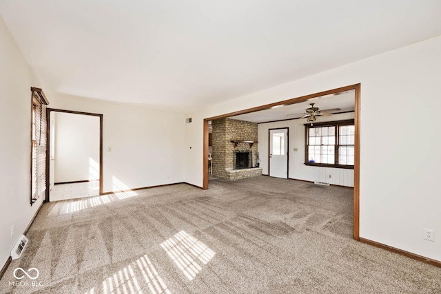 unfurnished living room featuring visible vents, a ceiling fan, carpet flooring, baseboards, and a brick fireplace