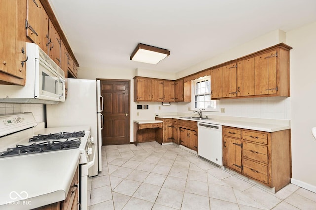 kitchen with white appliances, brown cabinetry, tasteful backsplash, and a sink