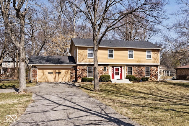 colonial home with brick siding, a front yard, and a garage