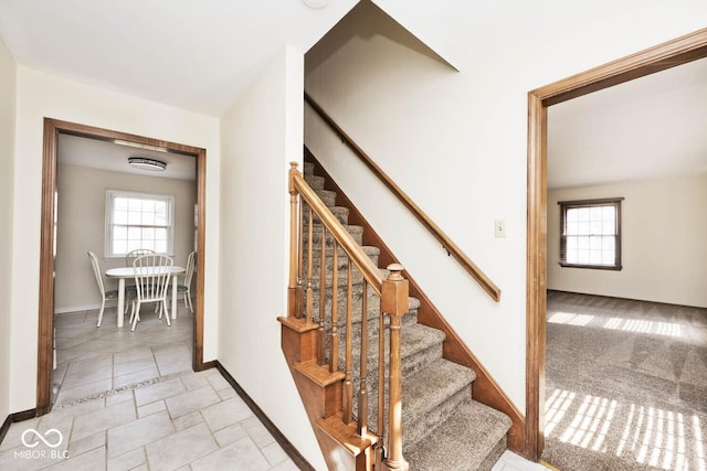 staircase featuring baseboards and plenty of natural light