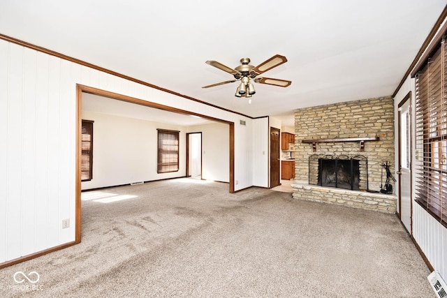 unfurnished living room with ornamental molding, a ceiling fan, carpet flooring, baseboards, and a brick fireplace