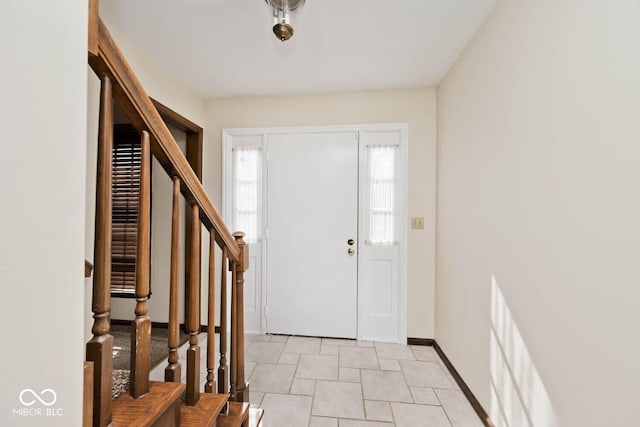 foyer entrance with stairway and baseboards