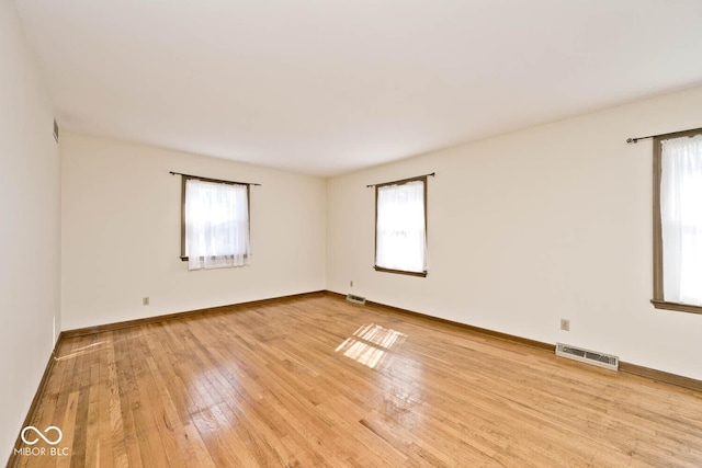 unfurnished room with visible vents, plenty of natural light, and light wood finished floors