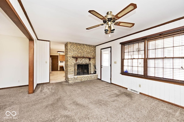 unfurnished living room featuring carpet, visible vents, a fireplace, ceiling fan, and crown molding