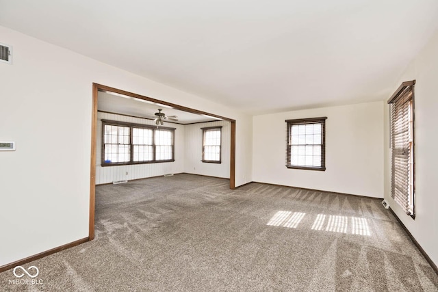 empty room with visible vents, baseboards, ceiling fan, and carpet flooring