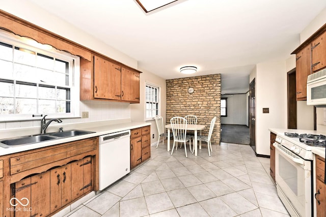 kitchen with a sink, white appliances, a healthy amount of sunlight, and light countertops