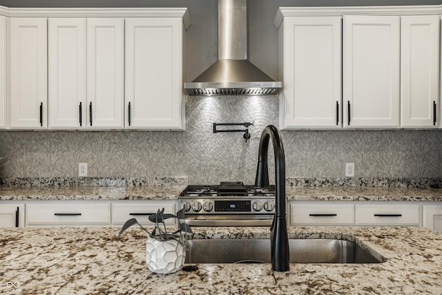 kitchen featuring white cabinetry, light stone countertops, and wall chimney exhaust hood