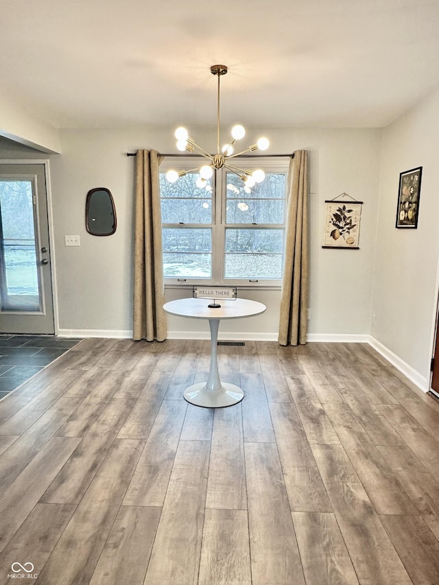 unfurnished dining area featuring hardwood / wood-style flooring and an inviting chandelier