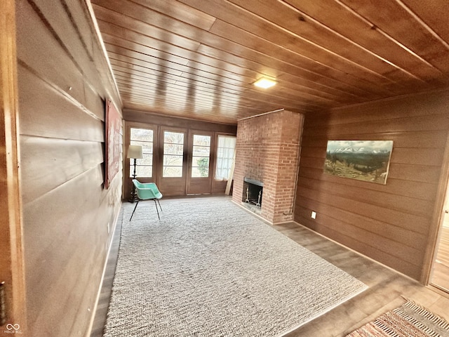 unfurnished living room featuring a brick fireplace, wooden ceiling, and wood walls