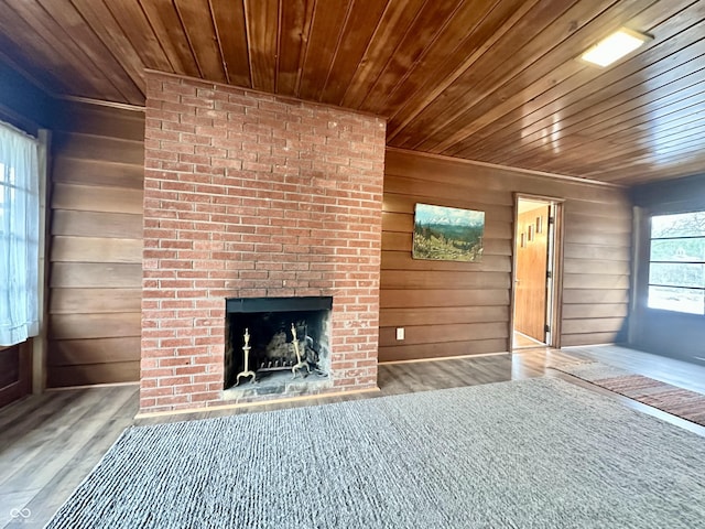 unfurnished living room featuring wood ceiling, an outdoor brick fireplace, wooden walls, and light hardwood / wood-style flooring