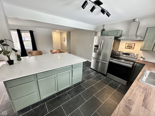 kitchen featuring sink, green cabinetry, wall chimney exhaust hood, and appliances with stainless steel finishes