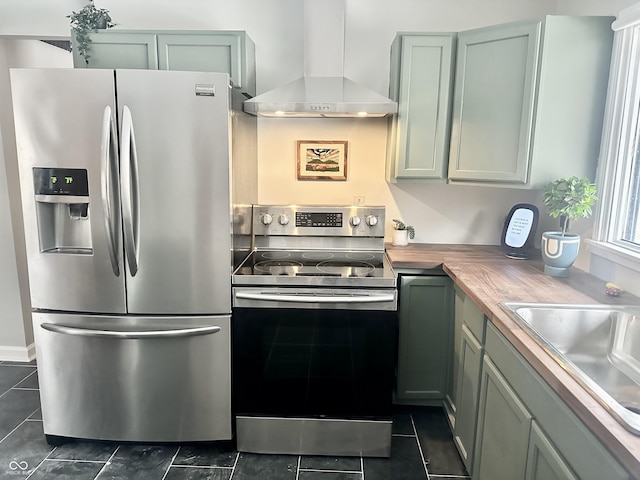 kitchen with wood counters, stainless steel appliances, sink, and wall chimney range hood