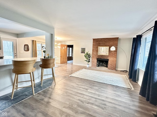 living room with wood-type flooring, a brick fireplace, and a healthy amount of sunlight