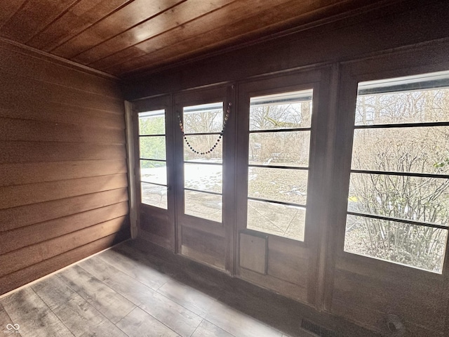 entryway with wood-type flooring, wooden ceiling, and wooden walls