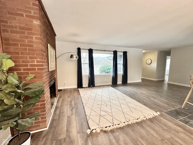 unfurnished living room featuring dark hardwood / wood-style floors and a brick fireplace